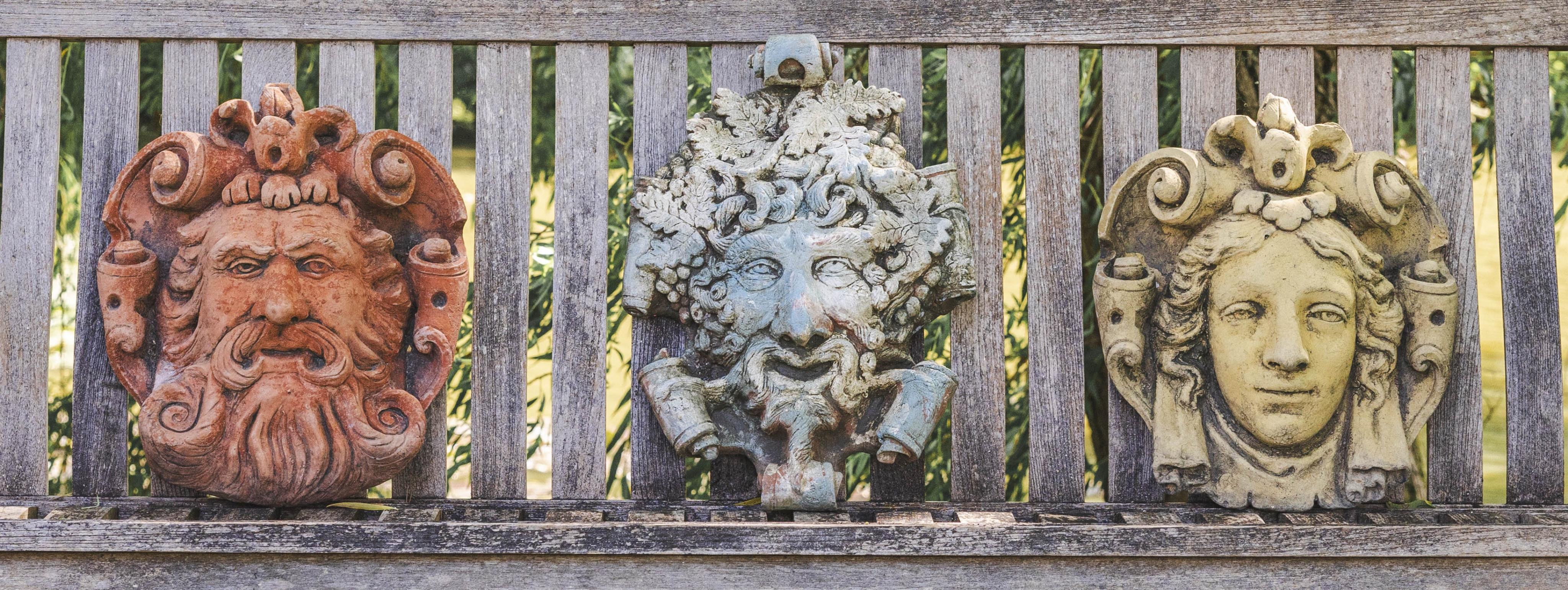 Three cast stone and terracotta garden wall mask appliqués, largest height 42cm